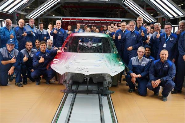 photo of a painted car inside new Hungarian paint shop of BMW along with its staff